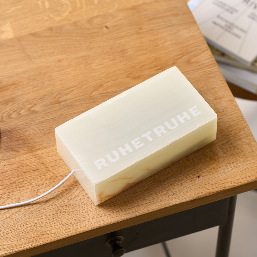 Geschlossene helle Ruhetruhe mit Ladekabel auf Holz